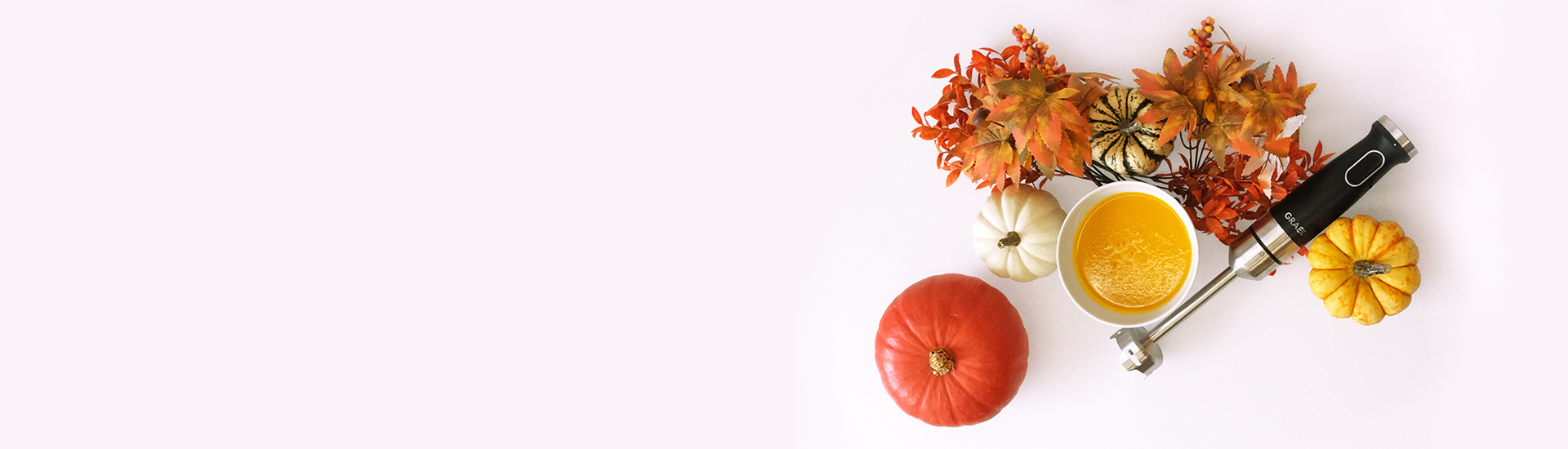 Mixeur plongeant avec soupe au potiron, potirons et décoration automnale