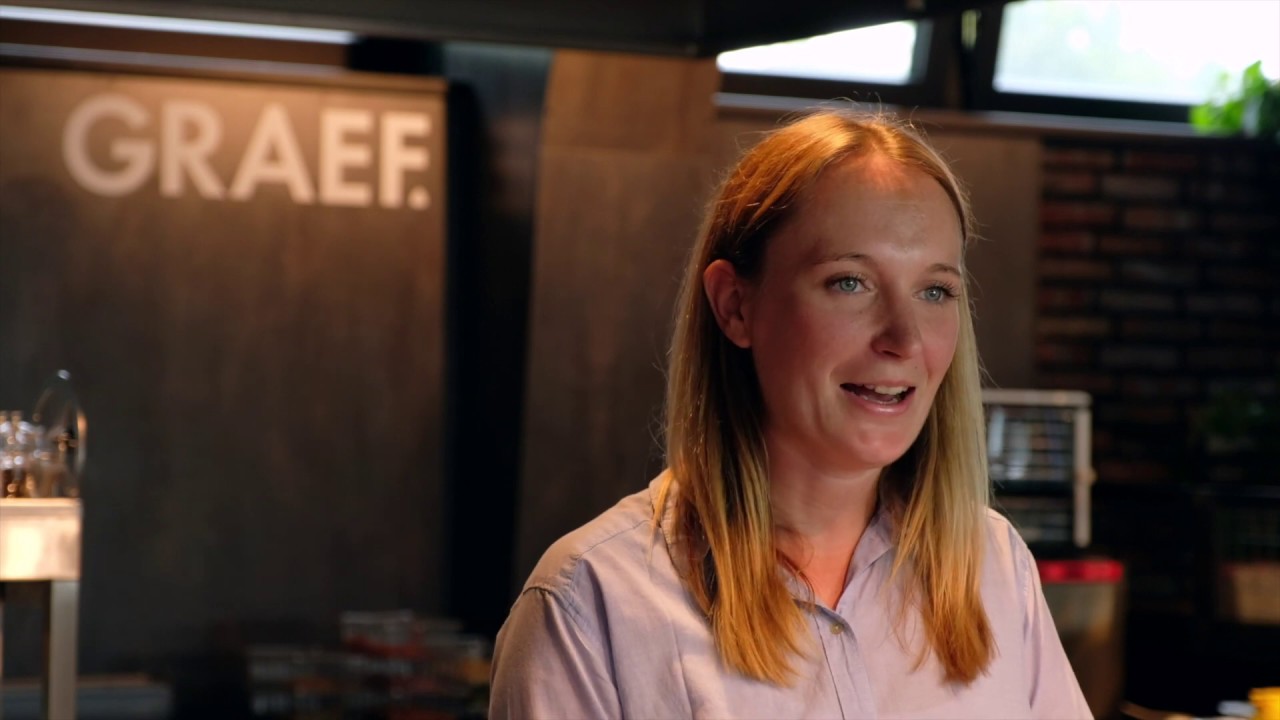 Eine Frau spricht vor einem GRAEF-Logo in einem Restaurant.
