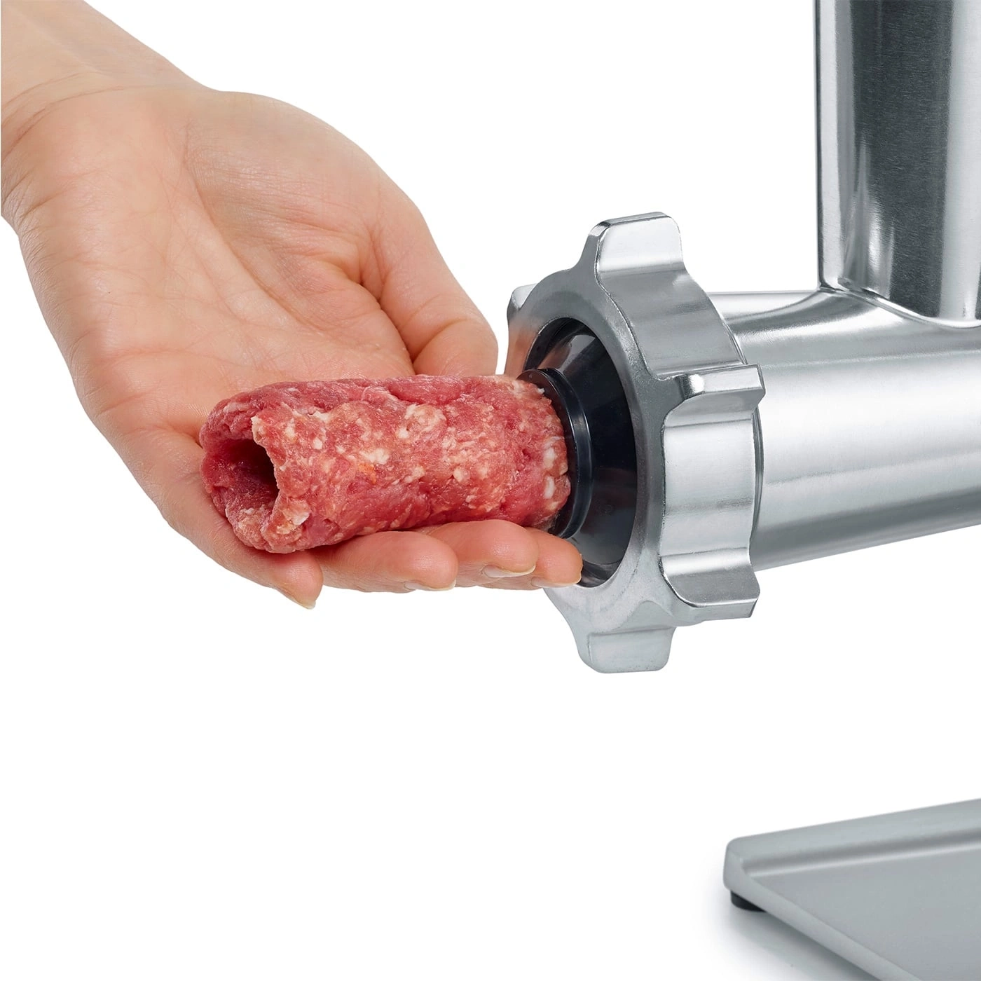 Hand holding meat being inserted into a meat grinder, close-up shot