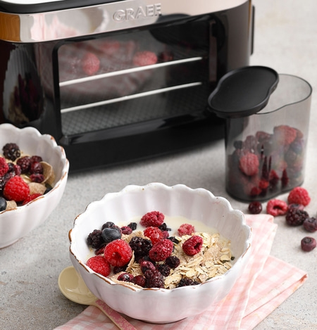 Breakfast with berries and cereal, next to a dehydrator and berry container