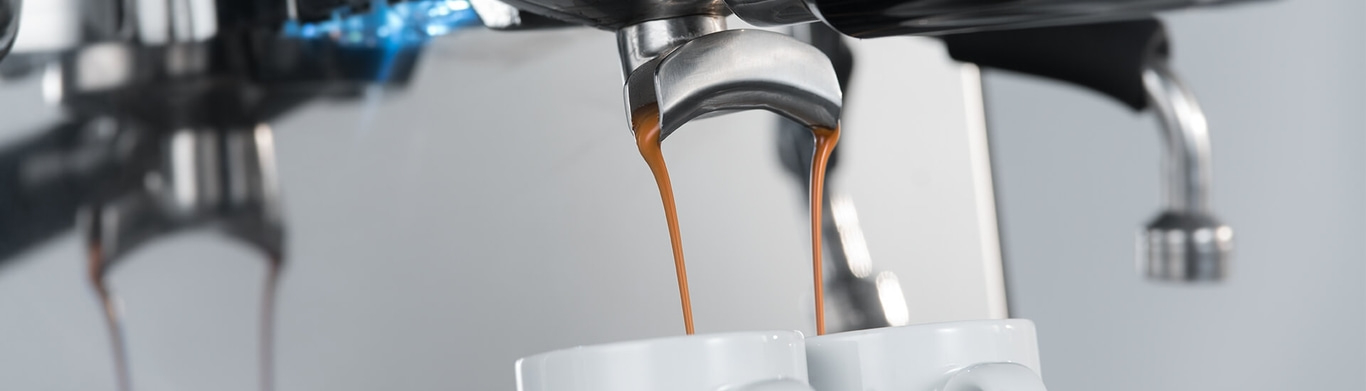 Nahaufnahme einer Espressomaschine, die Kaffee in Tassen gießt. Kaffeezubereitung.