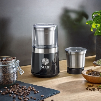Kaffeemühle mit Zubehör und Kaffeebohnen auf einem Holztisch