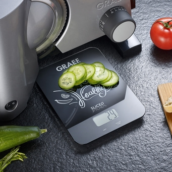 Gemüseschneider mit Waage und Gurkenscheiben, Tomate, gesundes Essen.