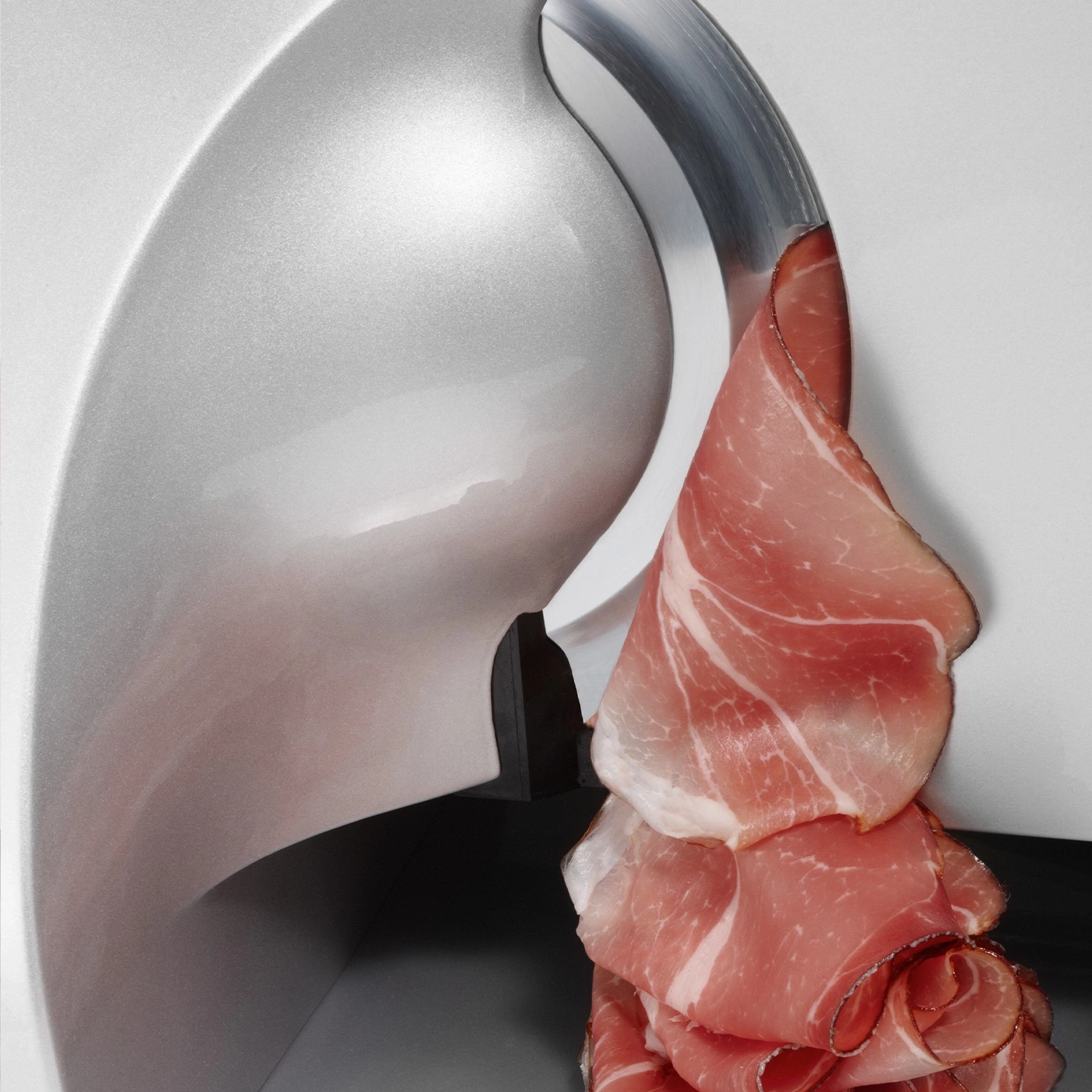 Une trancheuse à viande coupe de fines tranches de jambon.