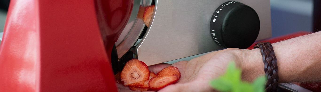 Erdbeeren werden mit einer Maschine geschnitten, Nahaufnahme, rote Farbe, Hand, Armband