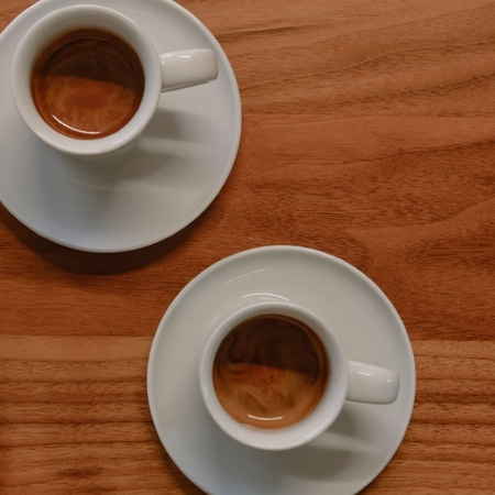 Zwei Tassen Kaffee auf Untertassen auf einem Holztisch