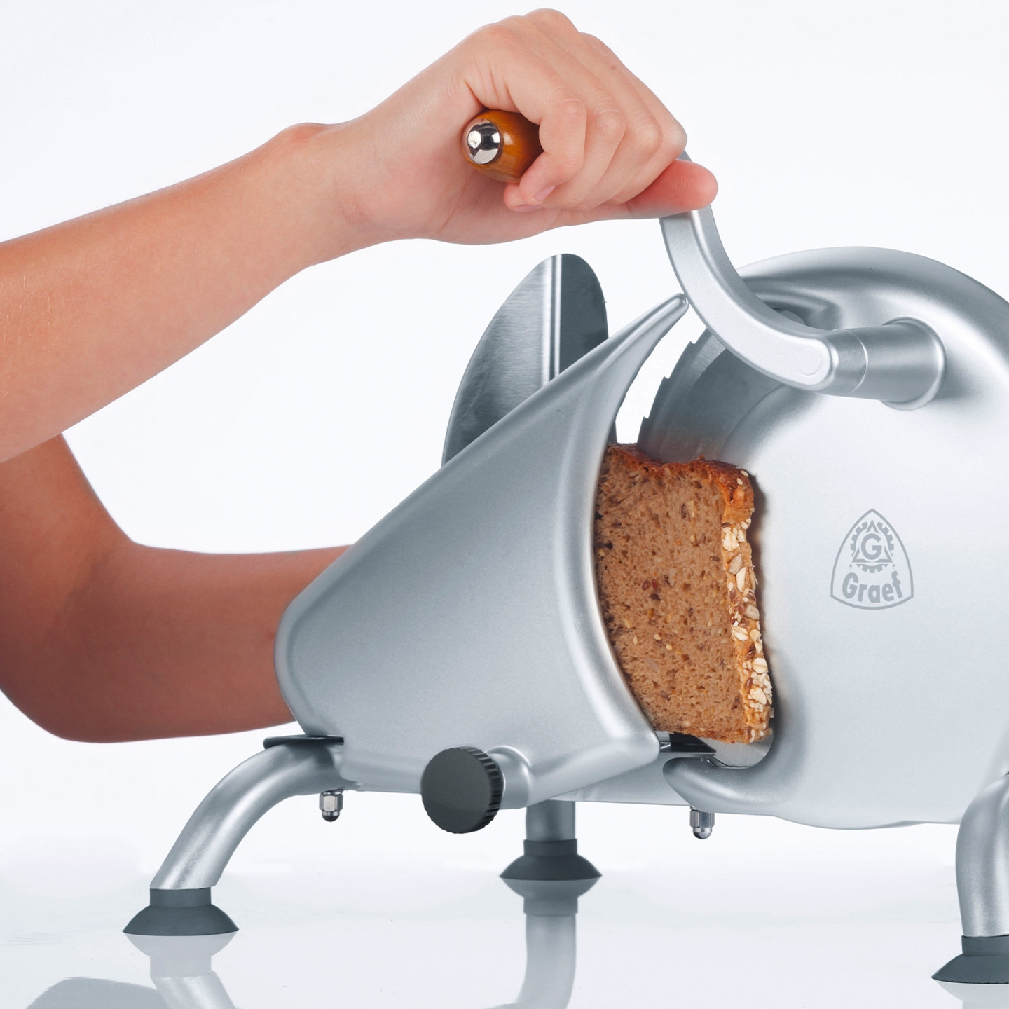 Person cutting bread with a slicer, close-up, Graet logo, silver machine, food