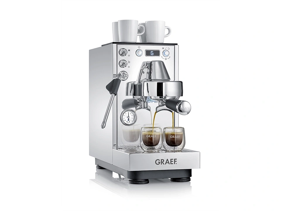 Eine glänzende Chrom-Espressomaschine mit zwei Tassen darauf und Espresso, der in Gläser fließt.