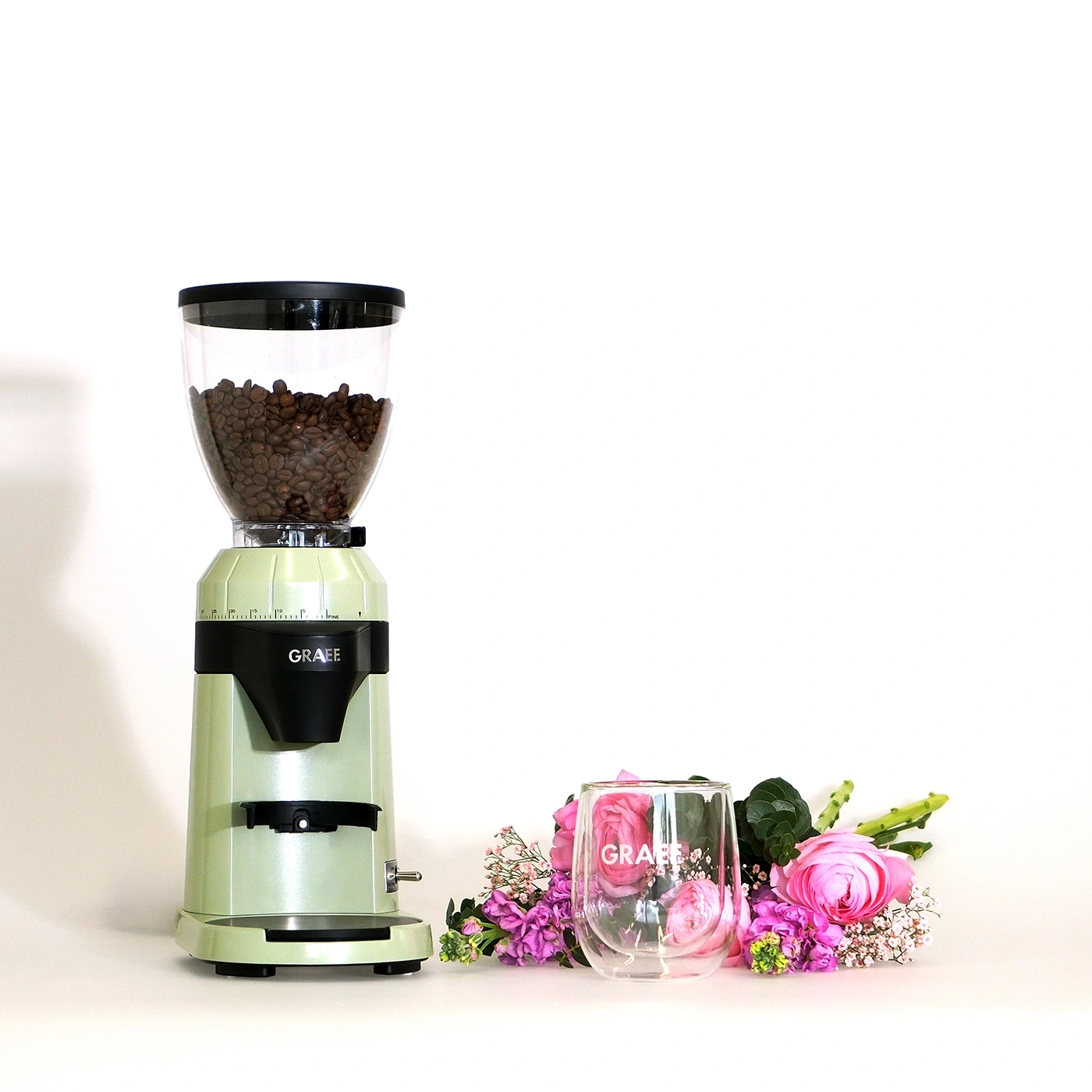 Kaffeemühle mit Glas und Blumen auf weißem Hintergrund. GRAEF.