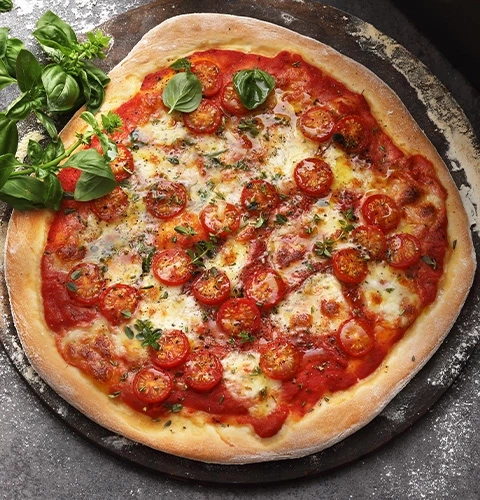 Gros plan d'une pizza aux tomates et au basilic servie sur une planche de bois