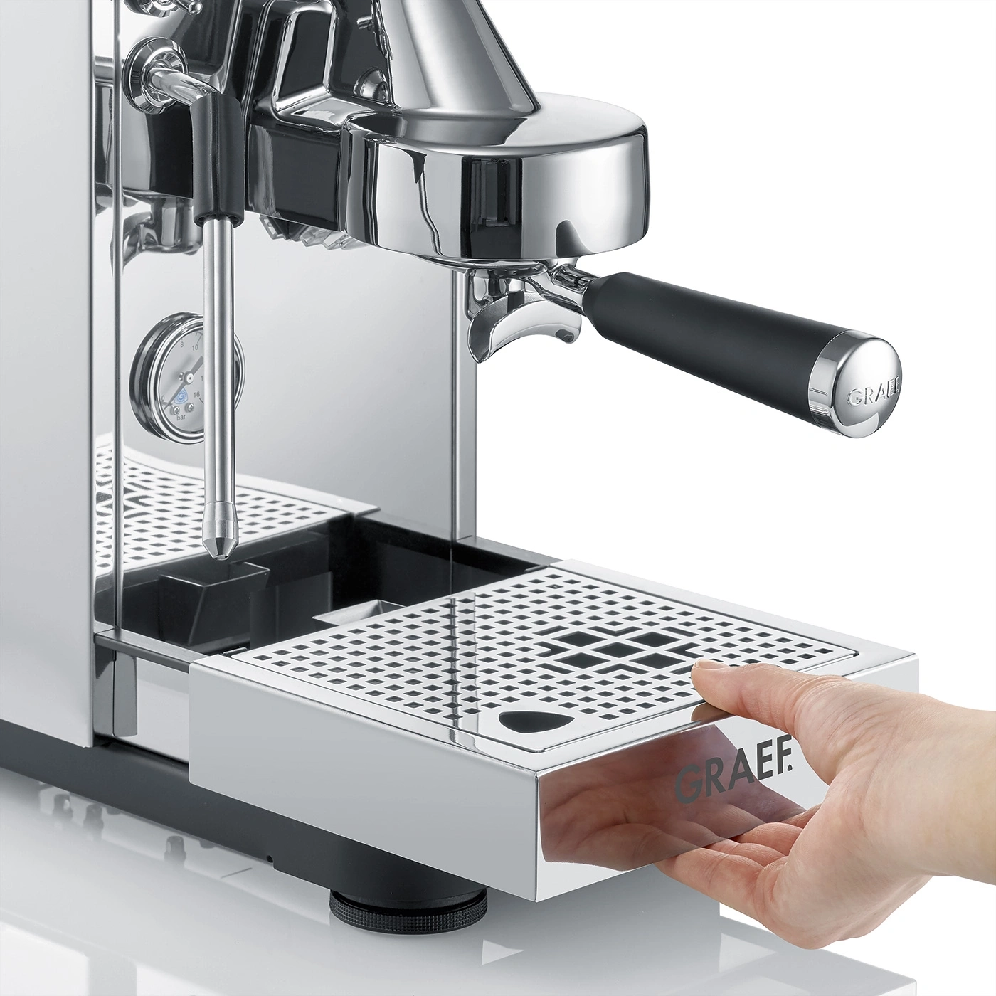 A hand pulls out the drip tray of a coffee machine.