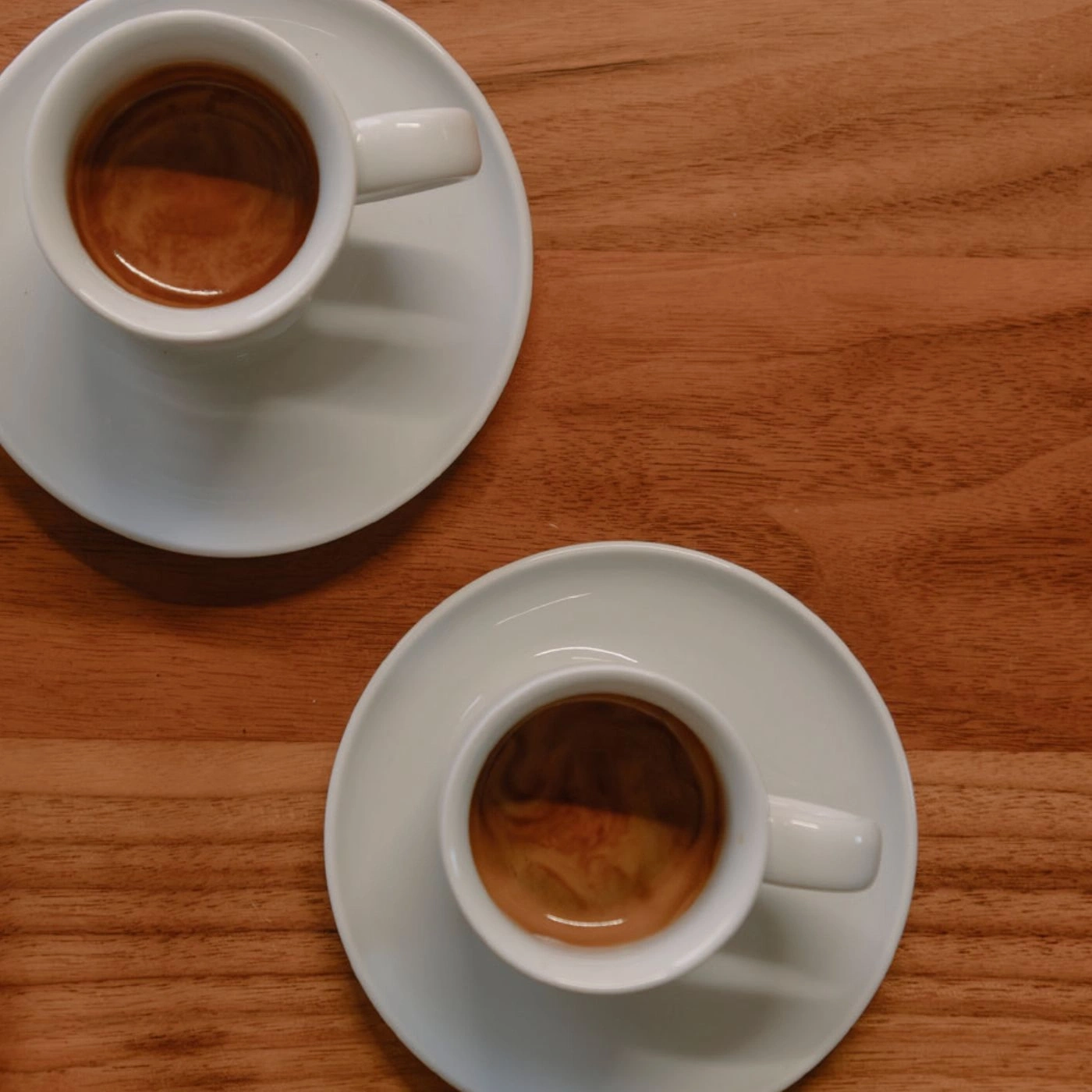 Zwei Tassen Kaffee auf Untertassen auf einem Holztisch