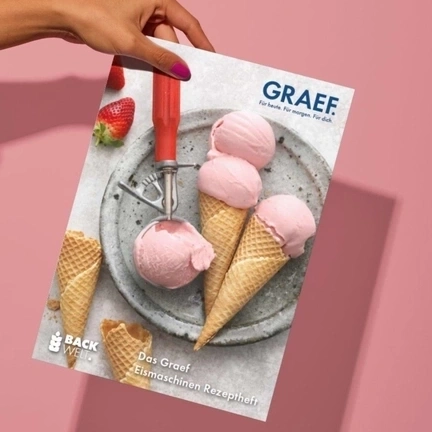 Main tenant un magazine avec des cornets de glace et des fraises sur fond rose