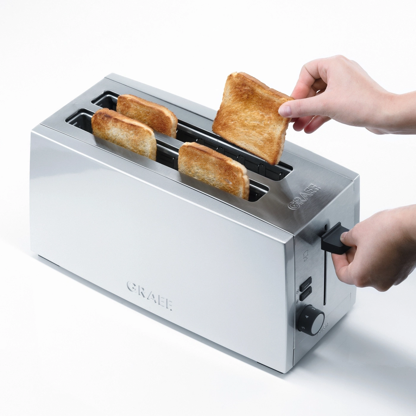 Ein Toaster mit Toast, der von einer Person herausgenommen wird, Nahaufnahme.