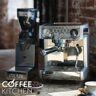 Coffee machine and grinder on a wooden table with coffee beans and a cup of coffee