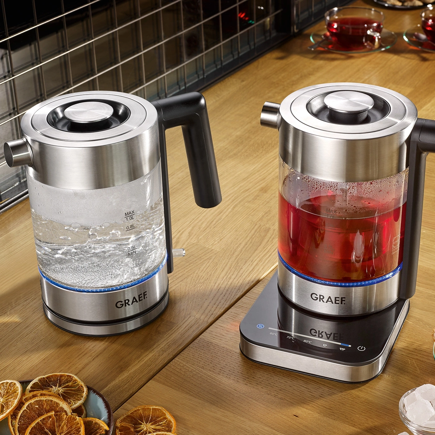 Zwei elektrische Wasserkocher mit Wasser und Tee auf einem Holztisch, GRAEF-Marke.