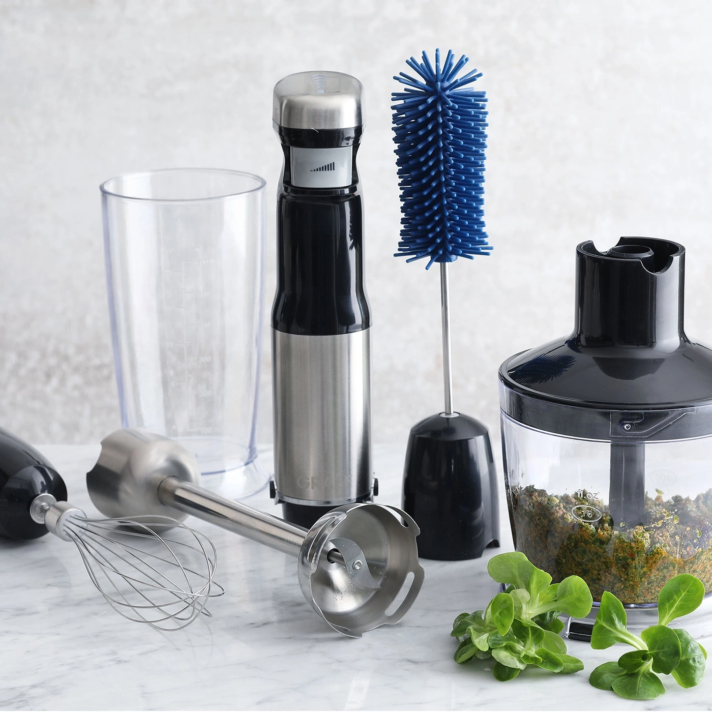 Küchenutensilien: Stabmixer, Becher, Schneebesen, Bürste, Gemüse, Mixerbehälter.