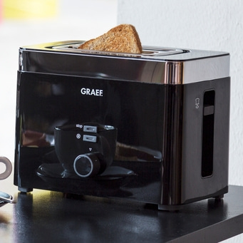 Schwarzer Toaster mit Toastbrot, Marke GRAEF, auf schwarzem Tisch