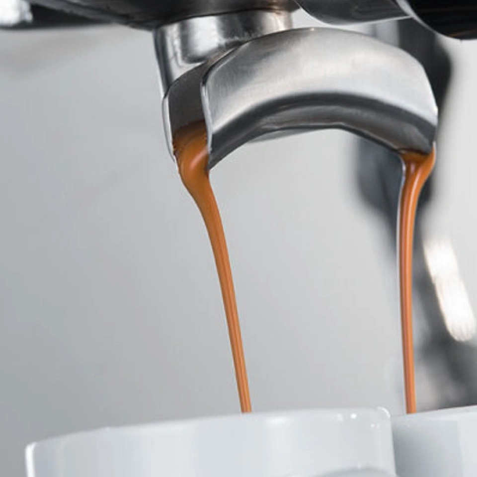 Nahaufnahme von Kaffee, der in Tassen aus einer Espressomaschine fließt.