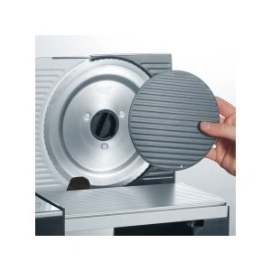 Gros plan d'une trancheuse à viande avec un disque de protection en main.