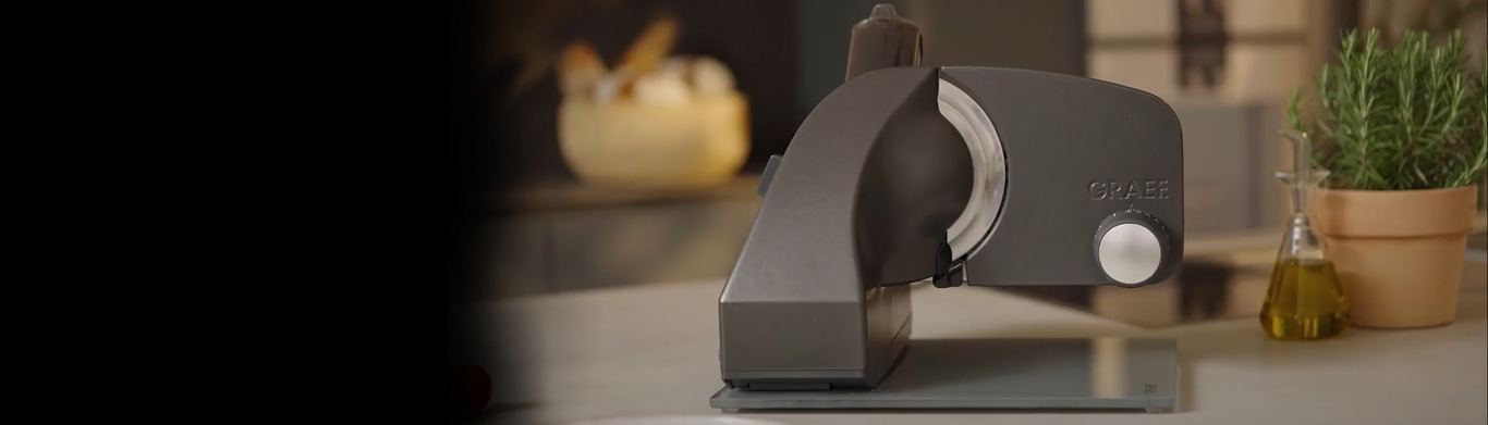 Graef slicer on a kitchen countertop with herbs and oil in the background.
