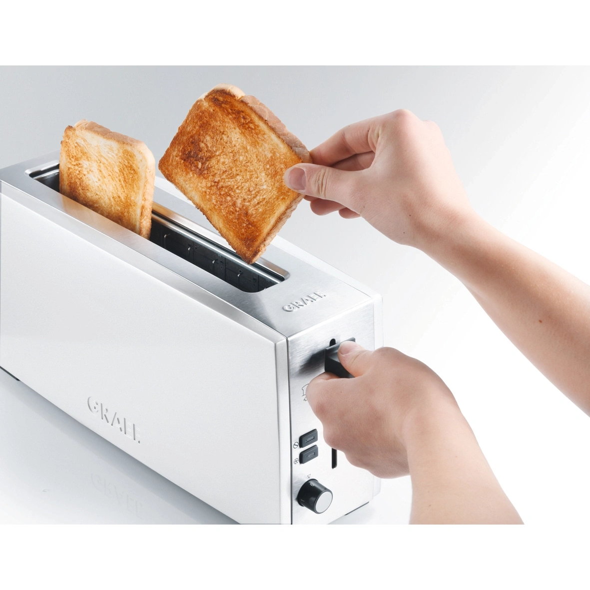 Ein Toaster mit zwei Toastscheiben, eine Hand nimmt eine Scheibe heraus.