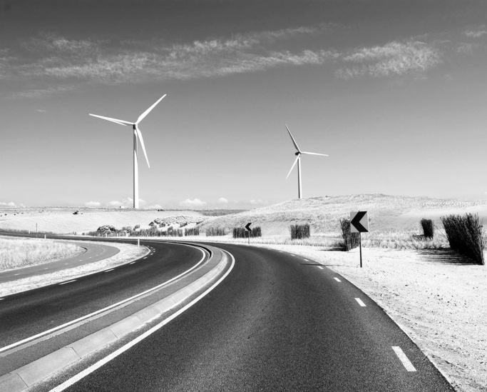 Windräder an einer kurvenreichen Straße unter blauem Himmel
