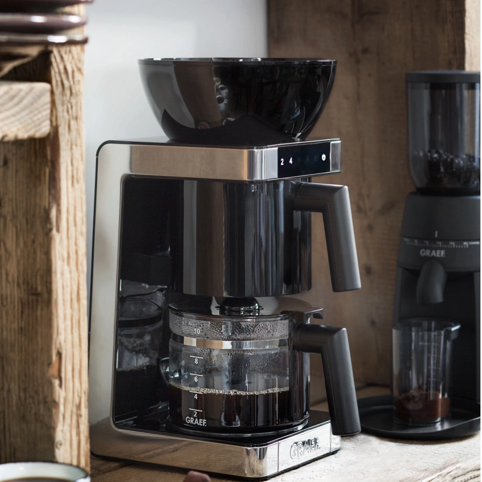 Coffee machine with grinder, glass carafe, black design, wooden surface, Graef logo, coffee brewing
