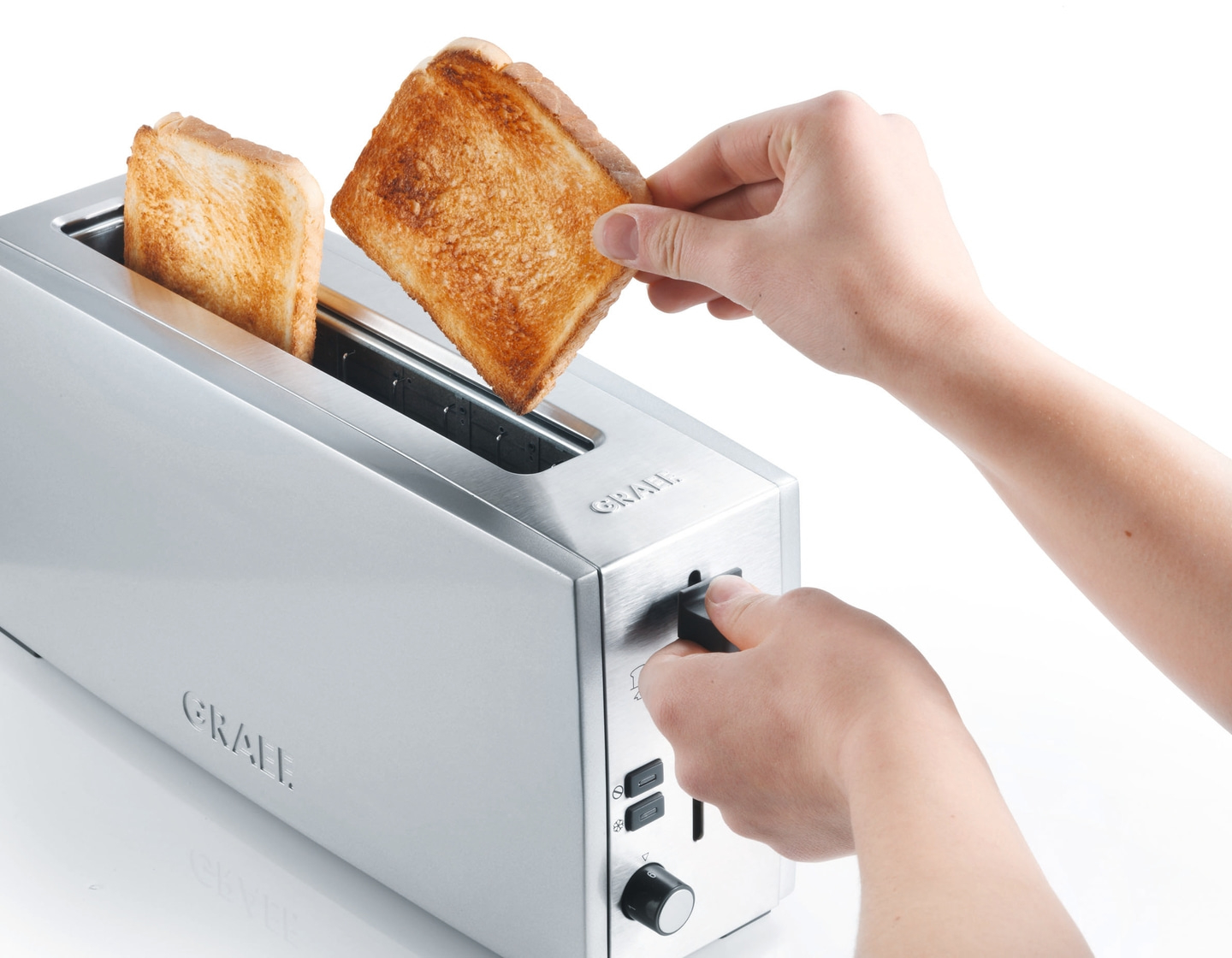 Person entnimmt Toast aus Toaster. Silberner Toaster mit Toastbrot.