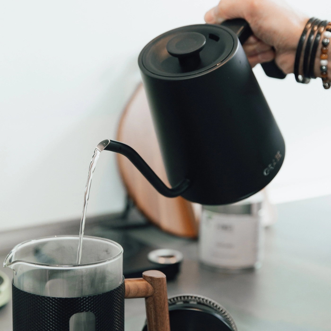 Schwarzer Wasserkocher gießt Wasser in eine Kaffeekanne, Nahaufnahme.