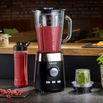 Graef blender with smoothie, berries and herbs on the counter top.