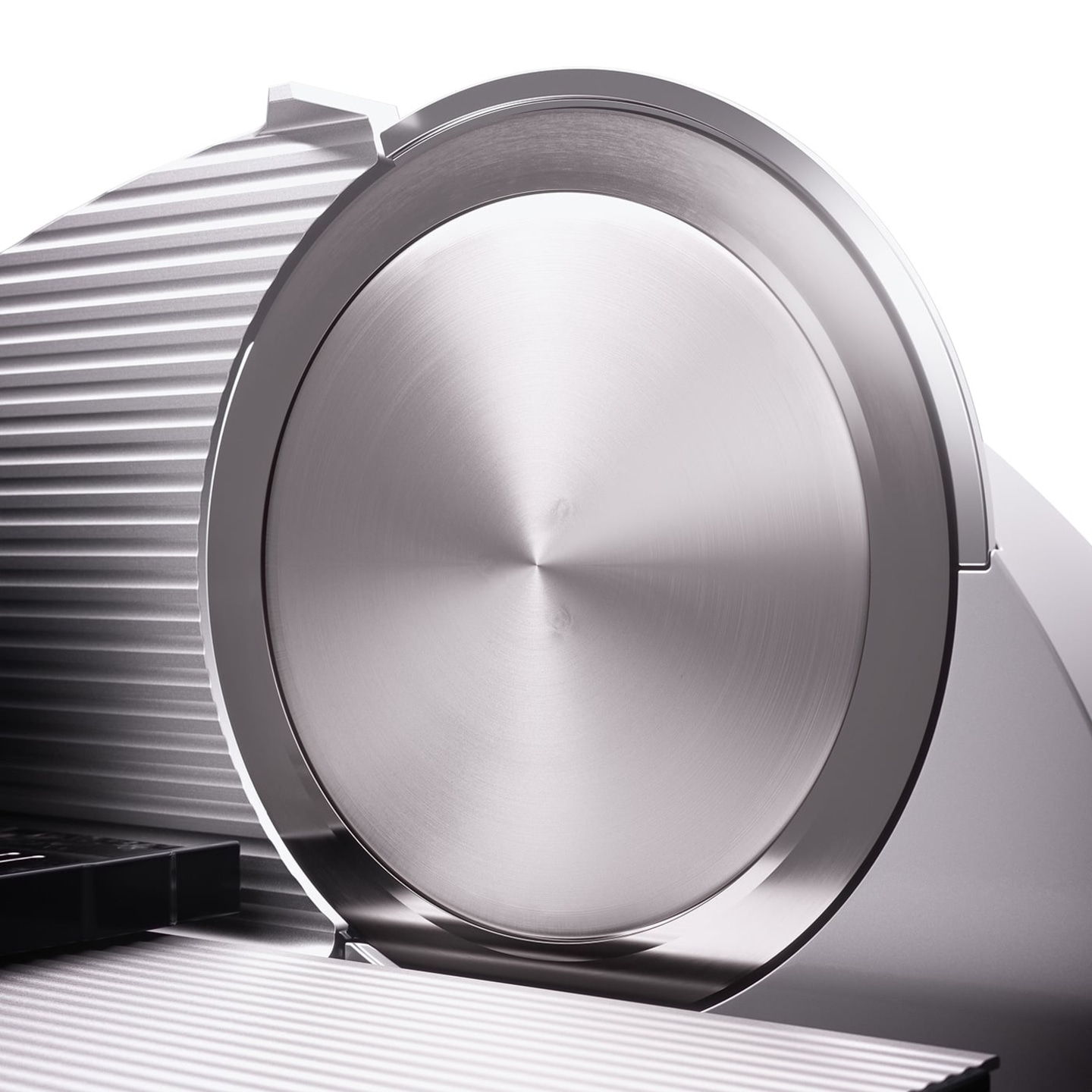 Close-up of a silver meat slicer with circular blade and ridged surface
