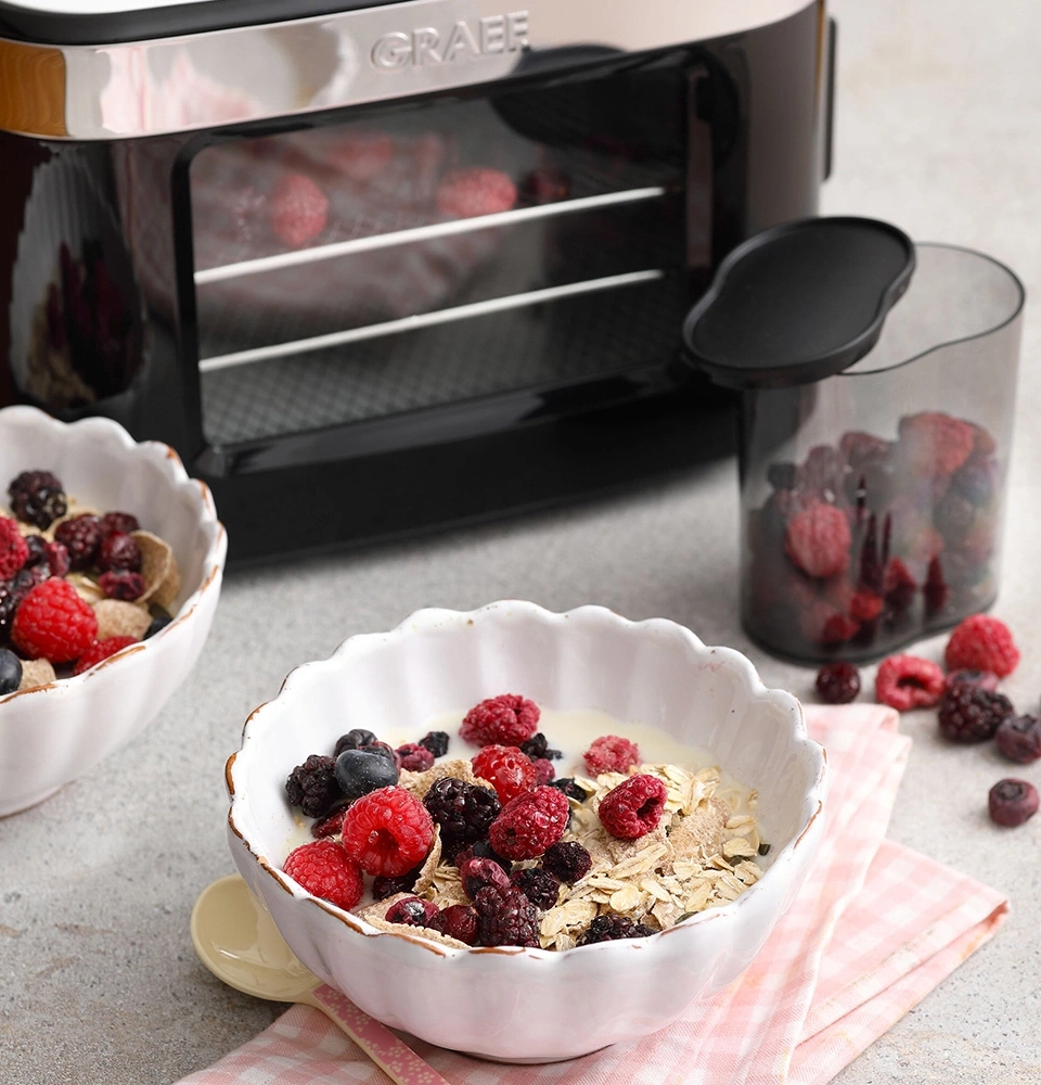 Breakfast with berries and cereal, next to a dehydrator and berry container