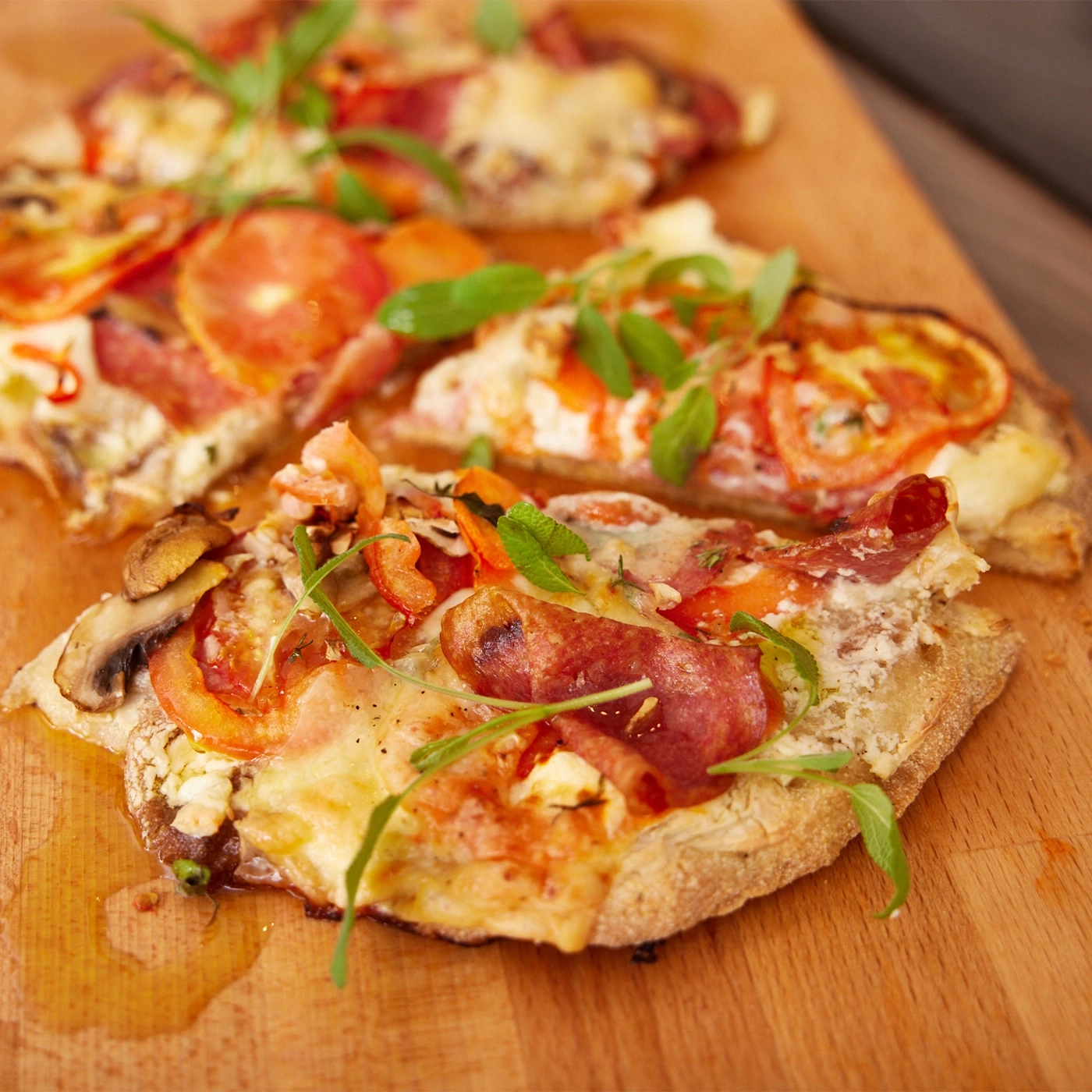 Gros plan de tranches de pizza avec tomates, fromage et herbes sur une planche de bois