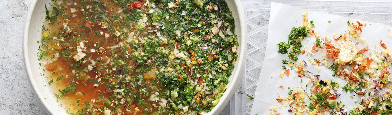 Bowl of soup and vegetables, with vegetables on paper next to it