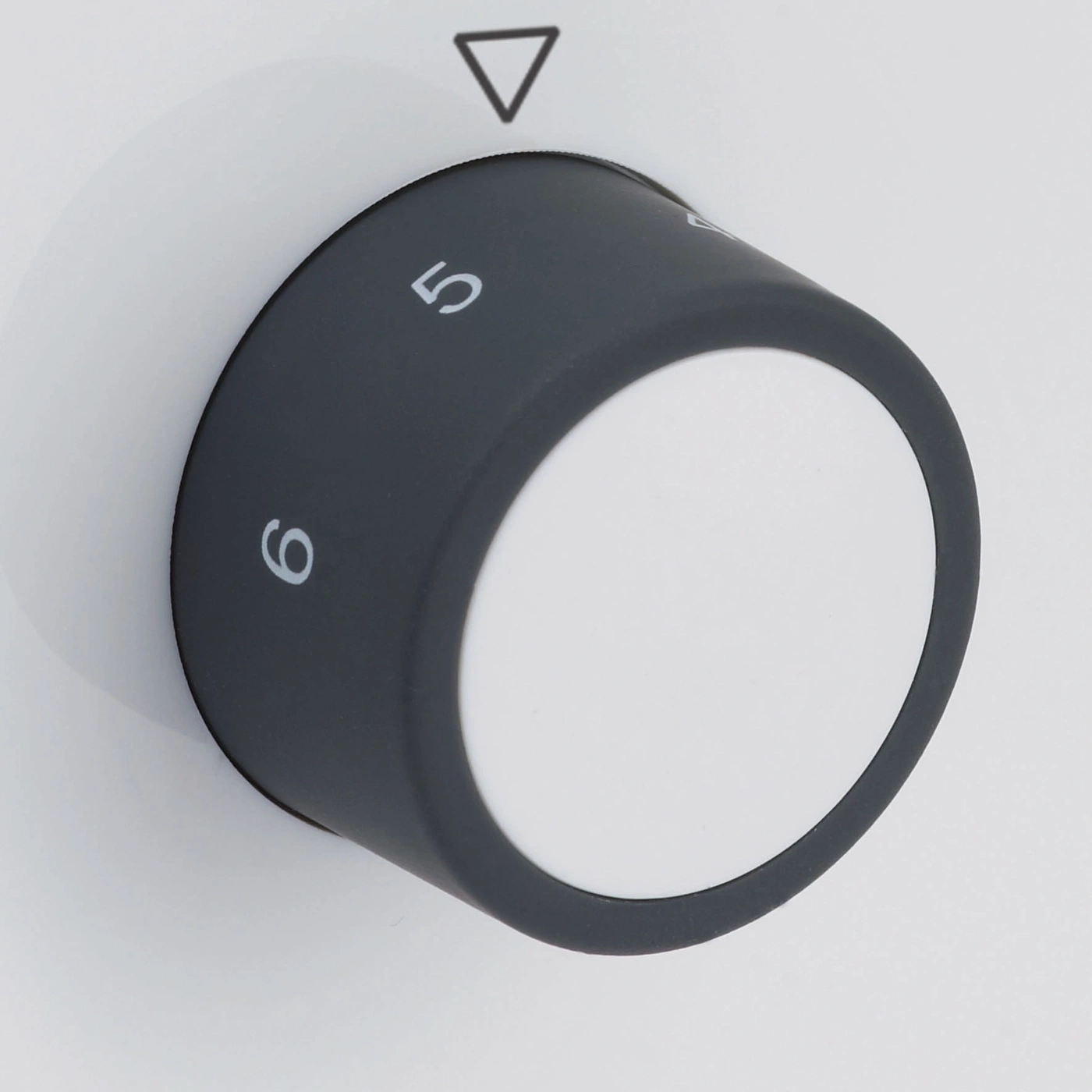 Close-up of a knob with numbers 5 and 6, white background, black arrow, detail shot