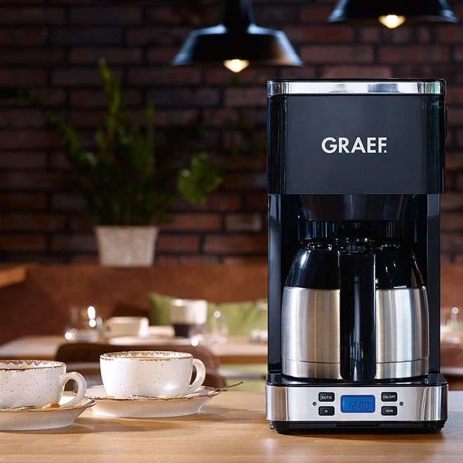 Kaffeemaschine mit Tassen auf einem Holztisch, GRAEF-Logo, Innenraum