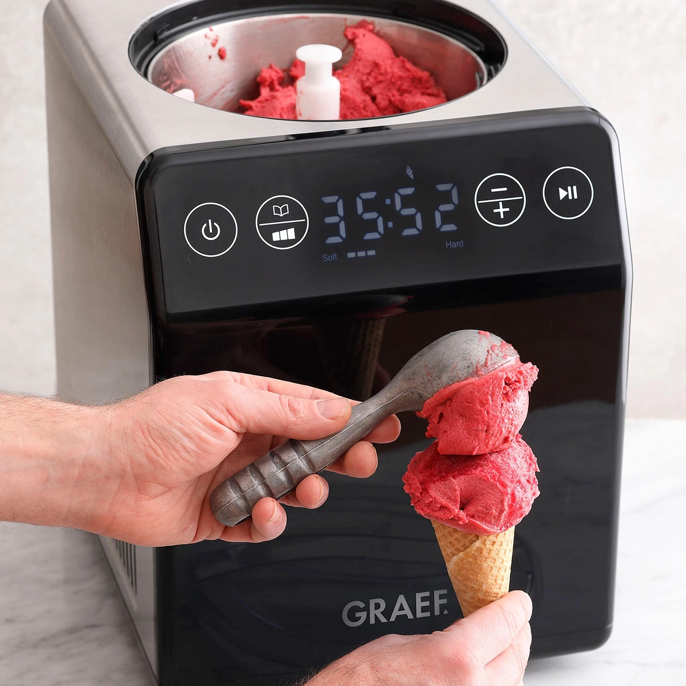 Machine à glace avec crème glacée, mains et cornet. Logo GRAEF.