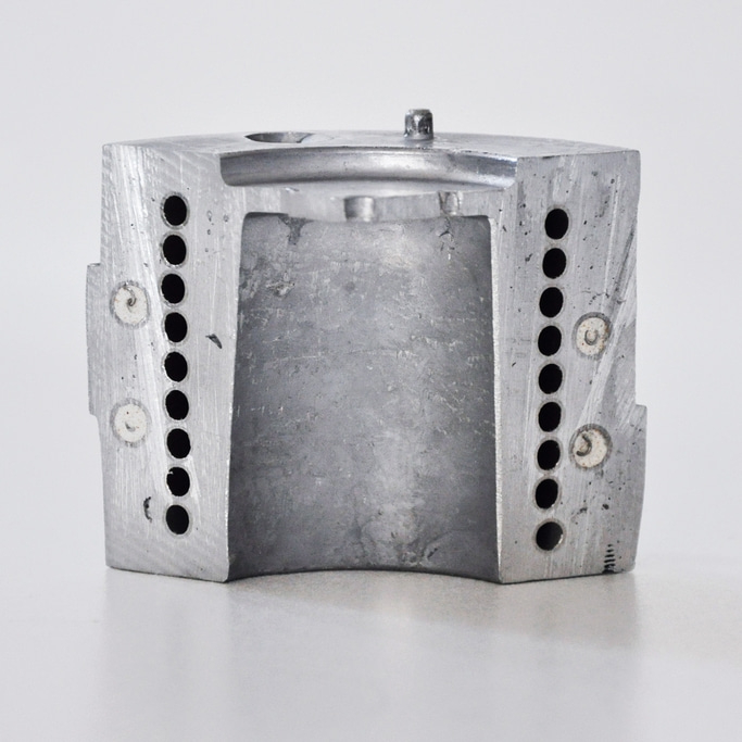 Metallblock mit Löchern und einem Loch in der Mitte, grau