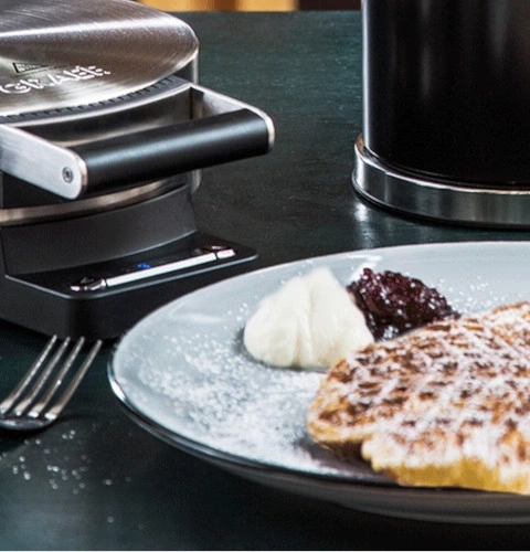 Gaufrier avec gaufre, crème et confiture sur une assiette