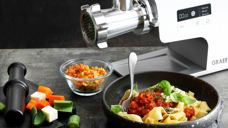 Fleischwolf mit Pasta, Gemüse und Tomatensauce auf einem Tisch