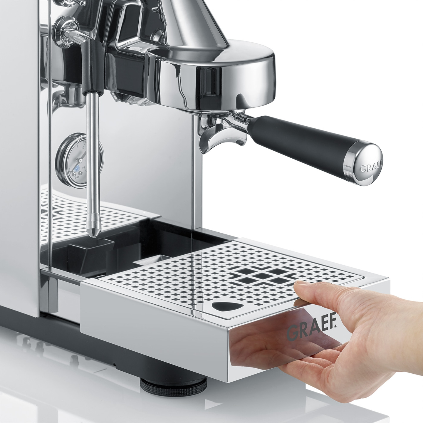 Eine Hand zieht die Abtropfschale einer Kaffeemaschine heraus.