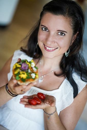 Lächelnde Frau hält Essen und Tomaten, Nahaufnahme, weißes Kleid, Schmuck