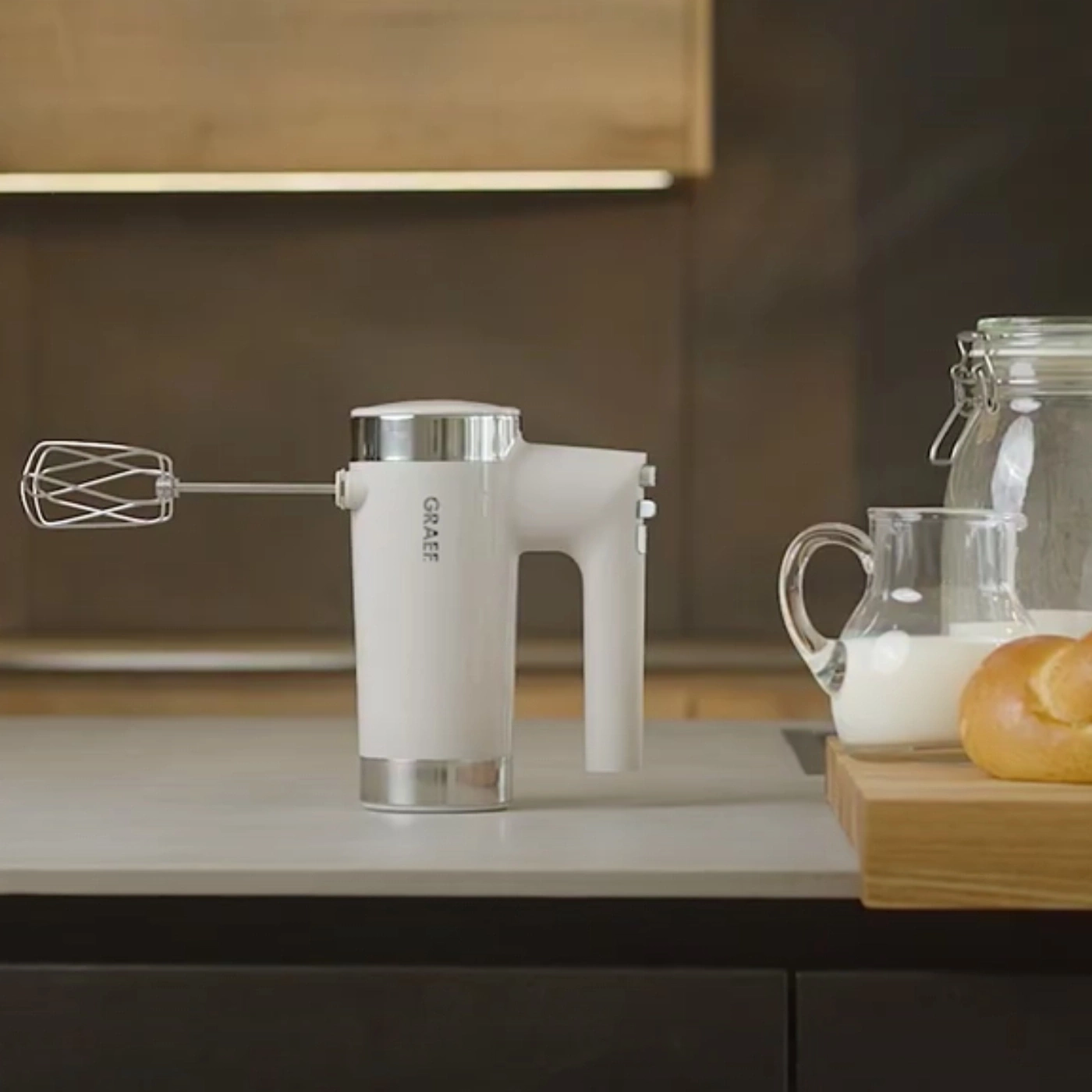 Mixeur à main blanc avec du lait et du pain sur un comptoir de cuisine.