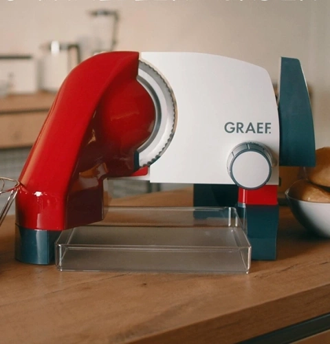 Trancheuse Graef rouge et blanche sur table en bois, cuisine en arrière-plan