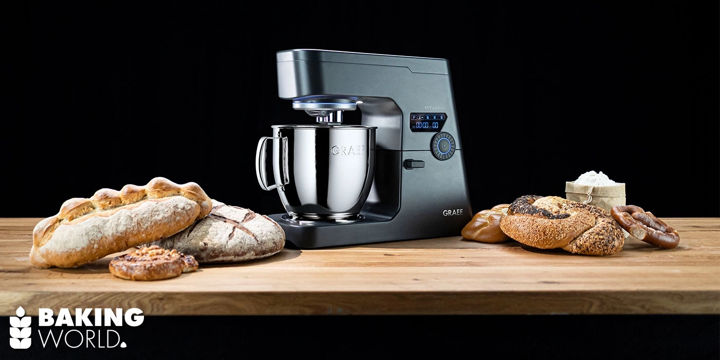 Robot culinaire avec du pain sur une planche en bois sur fond noir