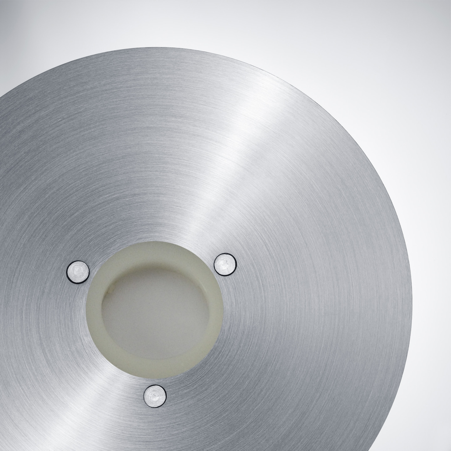 Circular metal part with screws and a hole in the middle, gray color
