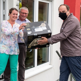 Personen erhalten ein Paket. Mann mit Maske übergibt Geschenk.