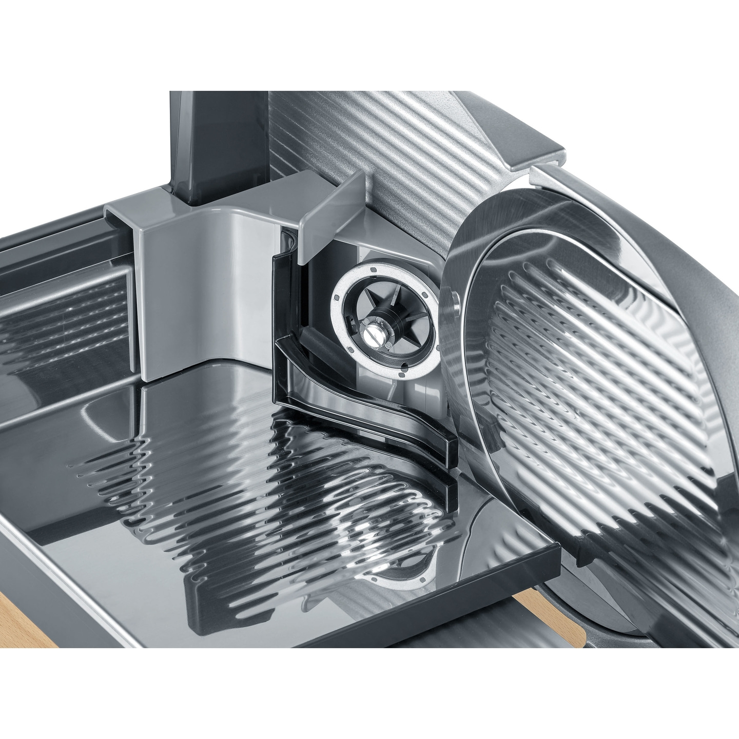 Close-up of a silver meat slicer with a wooden base and shiny surfaces