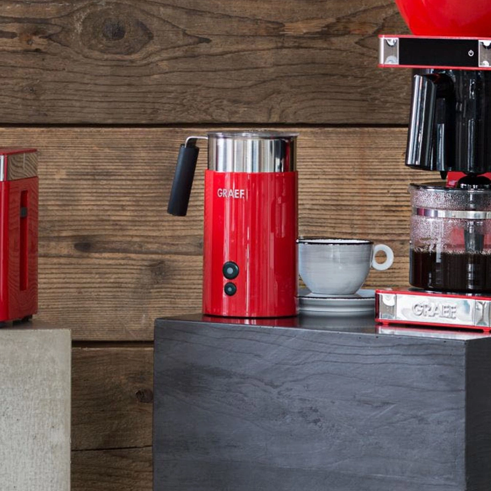 Red coffee machine and accessories on a dark table in front of wood